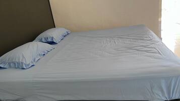 A bed with a grey headboard and two pillows.