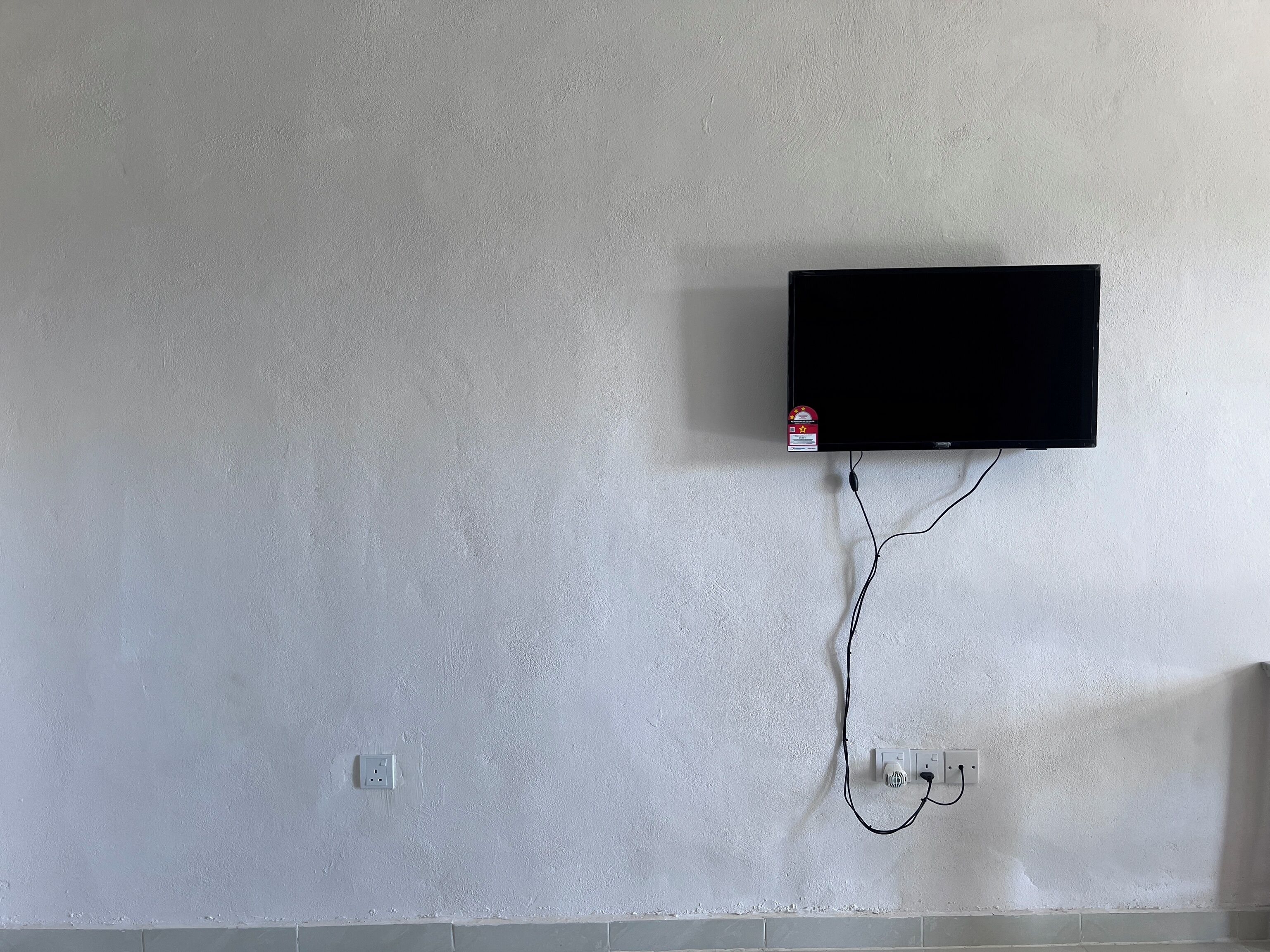 A wall-mounted TV with a cable connected to a power outlet.