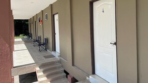 A corridor with doors numbered 4 and 5, leading to rooms with blue folding chairs outside. - Hotel O Sri Ayu Inn (Gurun)