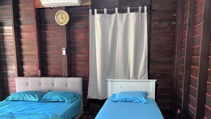 A room with two beds, each with blue bedding. There is a clock on the wall and a curtain on the window. - Hotel O Sri Ayu Inn (Gurun)