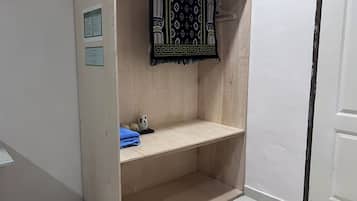 A small, enclosed bathroom with a wooden vanity, a towel rack, and a toilet paper holder.