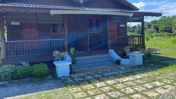 A wooden house with a porch, a small garden, and a clear sky. - Hotel O Sri Ayu Inn (Gurun)