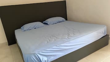 A bed with a dark headboard and a light blue mattress cover.
