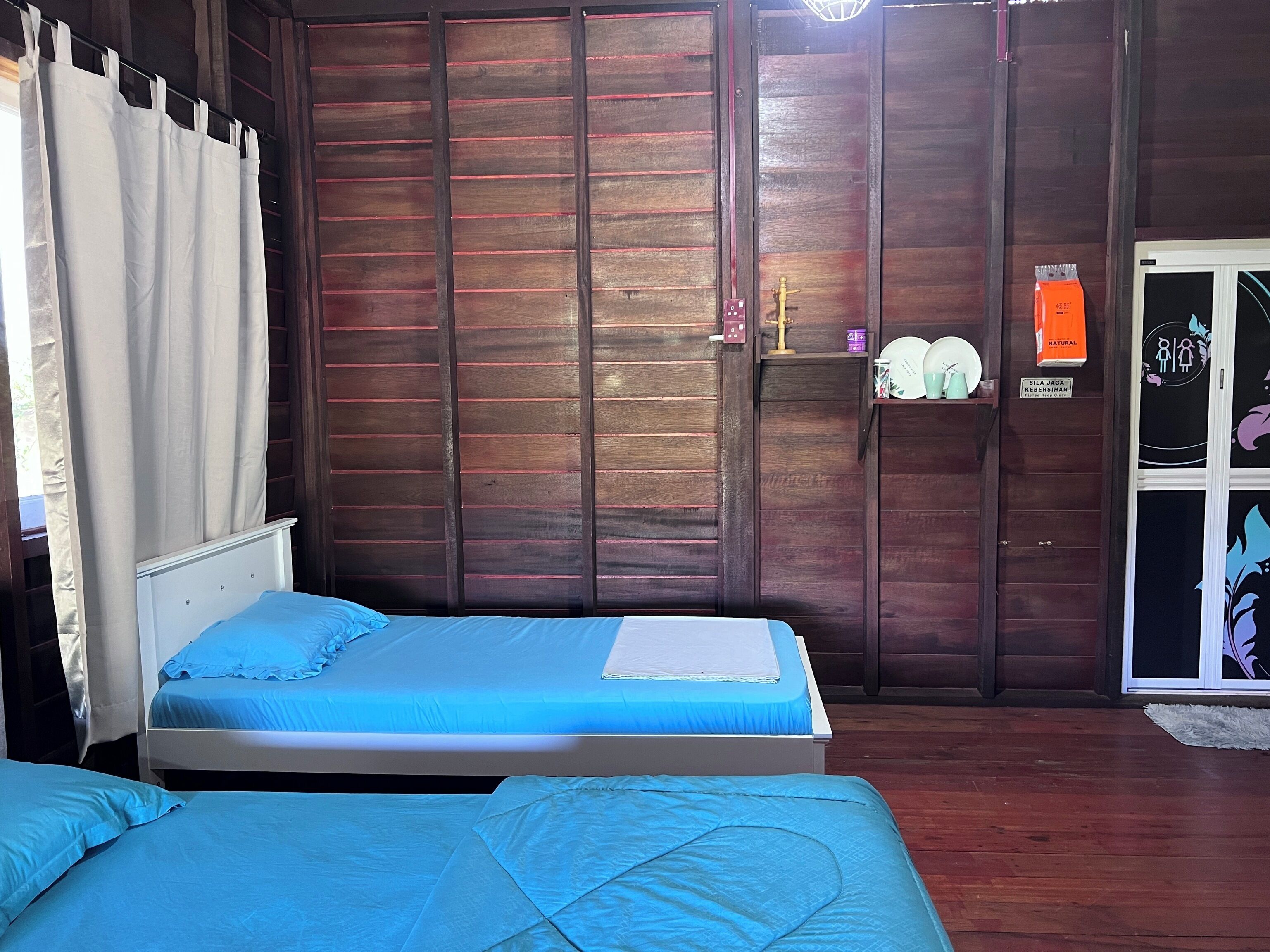 Un dormitorio con un armario de madera, una cama con ropa de cama azul y una pequeña estantería con artículos de aseo.