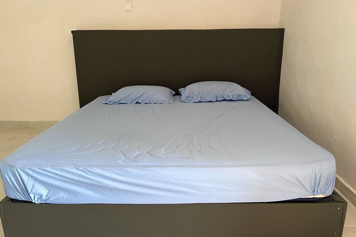 A bed with a dark headboard and light blue bedding.