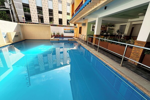 A hotel pool area with a clear blue pool, a sign for 'Sea Jewel Hotel', and a staircase leading to an upper level. - Sea Jewel Hotel Puerto Galera powered by Cocotel (Puerto Galera)