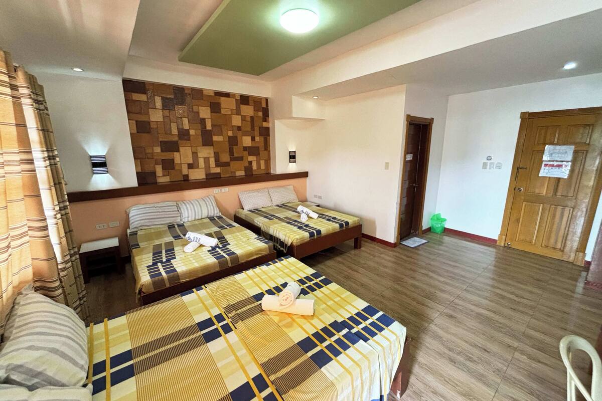 Une chambre d’hôtel avec deux lits, un plancher en bois, un mur orné d’un motif géométrique et une porte avec une pancarte.