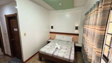 Un dormitorio con una cama, una mesita de noche, una lámpara de pared y una puerta.
