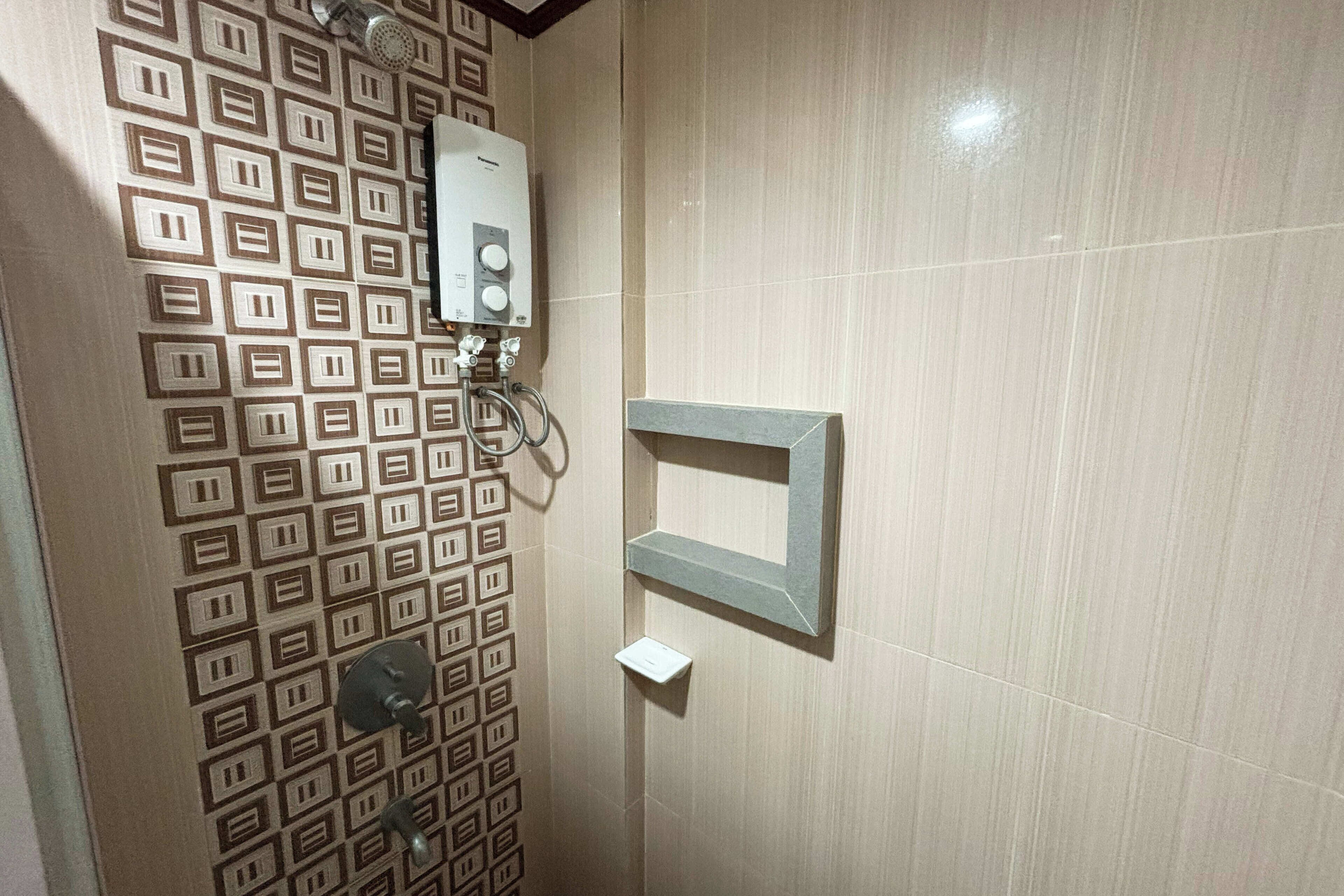 Un baño con baldosas estampadas, una ducha y un perchero para toallas.