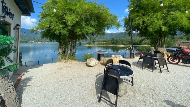 Un espace extérieur aménagé avec des tables et des chaises, offrant une vue sur un lac et entouré d’arbres.