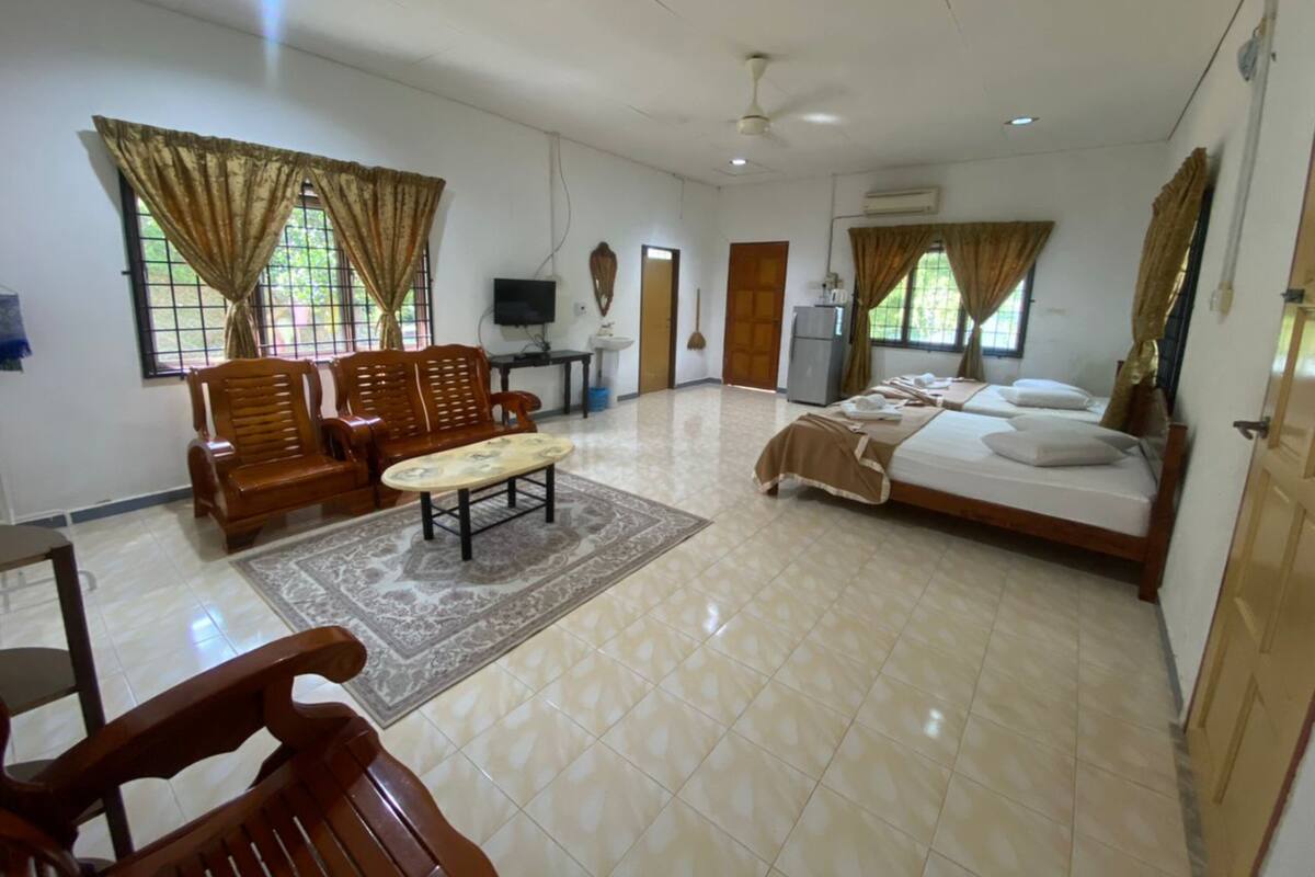 A spacious room with a large bed, two wooden chairs, a small table, and a TV.