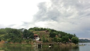 Une propriété au bord du lac comprenant plusieurs maisons, un quai et une colline boisée.