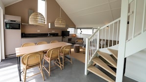 Une cuisine moderne avec un coin repas, un escalier et une grande fenêtre.