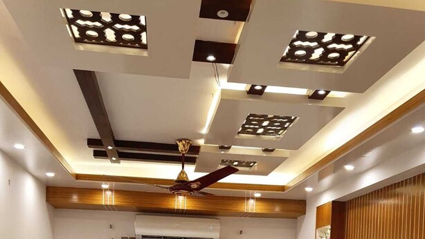 Un salon moderne avec un canapé d’angle, un téléviseur à écran plat et un ventilateur de plafond.