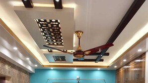 Un coin repas avec une table et des chaises en bois, un ventilateur de plafond et un luminaire fixé au mur.