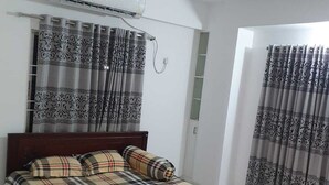 Une chambre à coucher avec un lit, des rideaux, un ventilateur de plafond et un appareil de climatisation.