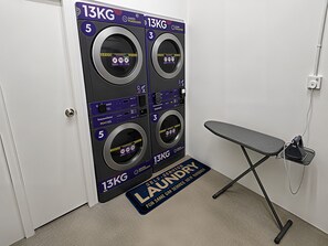 A self-service laundry area with two 13KG washing machines, a drying station, and a folding station. - Space Hotel KL Sentral (Kuala Lumpur)