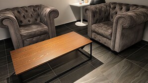 Uma sala de estar moderna com dois sofás estofados, uma mesa redonda pequena e uma mesa lateral com uma planta em vaso.