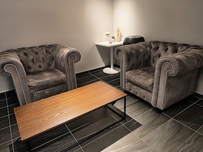 A modern living room with two tufted sofas, a small round table, and a side table with a potted plant. - Space Hotel KL Sentral (Kuala Lumpur)