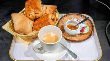 En bakke med en kop kaffe, en lille skål syltetøj og flere kager.