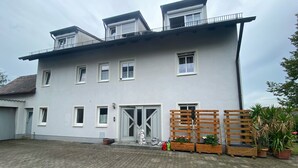 A two-story building with a flat roof, multiple windows, and a gated entrance. - Apartment 'Wohner' with Private Garden, Balcony and Wi-Fi (Petersaurach)