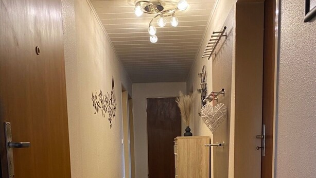 A hallway with wooden flooring, a ceiling light fixture, and a door on the left. - Apartment 'Wohner' with Private Garden, Balcony and Wi-Fi (Petersaurach)