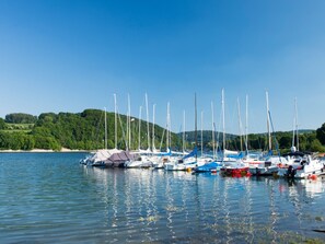 A marina with multiple sailboats docked, calm water, and a forested hillside in the background. - Apartment 'Fewo Wendelstein' with Shared Terrace, Shared Garden and Wi-Fi (Willingen (Upland))