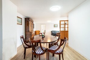 A dining area with a round table, six chairs, a cabinet, and a sofa.