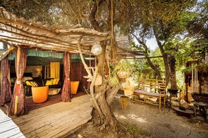 Un espace extérieur aménagé avec du mobilier en bois et une partie couverte par des rideaux.