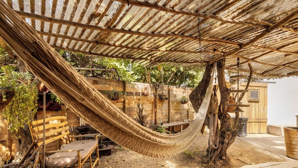 A hammock under a wooden pergola in a rustic outdoor setting with a wooden bench and a rustic table. - Sultan's Tent at Caesarea by Sea N' Rent (Hof HaCarmel)