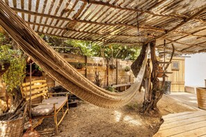 A hammock under a wooden pergola in a rustic outdoor setting with a wooden bench and a rustic table. - Sultan's Tent at Caesarea by Sea N' Rent (Hof HaCarmel)