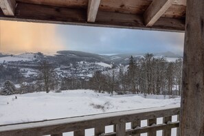 Paisatge nevós amb una terrassa de fusta i vista a turons coberts de neu.