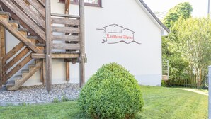 Un edificio con una escalera de madera, un letrero que dice 'Landhaus Alpena' y un césped bien cuidado.