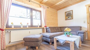 Un salón acogedor con un sofá marrón, una pequeña mesa de madera y una ventana con cortinas.