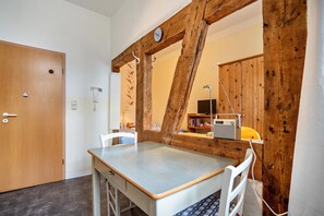 Um quarto com uma mesa de madeira, uma cadeira, uma porta de madeira e estrutura de vigas de madeira.
