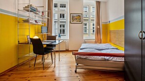 A bedroom with a bed, a desk with a chair, a bookshelf, and a window with curtains. - Studio Apartment 'Ferienwohnung Rügen' with Wi-Fi (Stralsund)