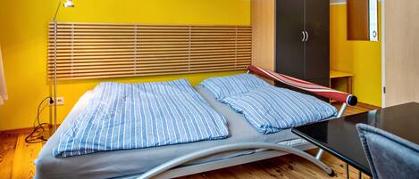 Quarto com cama, guarda-roupa, escrivaninha e luminária.