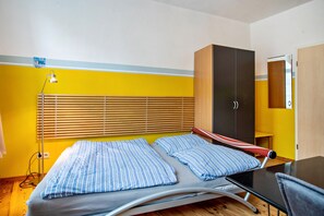 Una habitación con cama, armario, escritorio y lámpara.