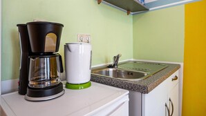 A kitchen with a coffee maker, a kettle, and a sink. - Studio Apartment 'Ferienwohnung Rügen' with Wi-Fi (Stralsund)