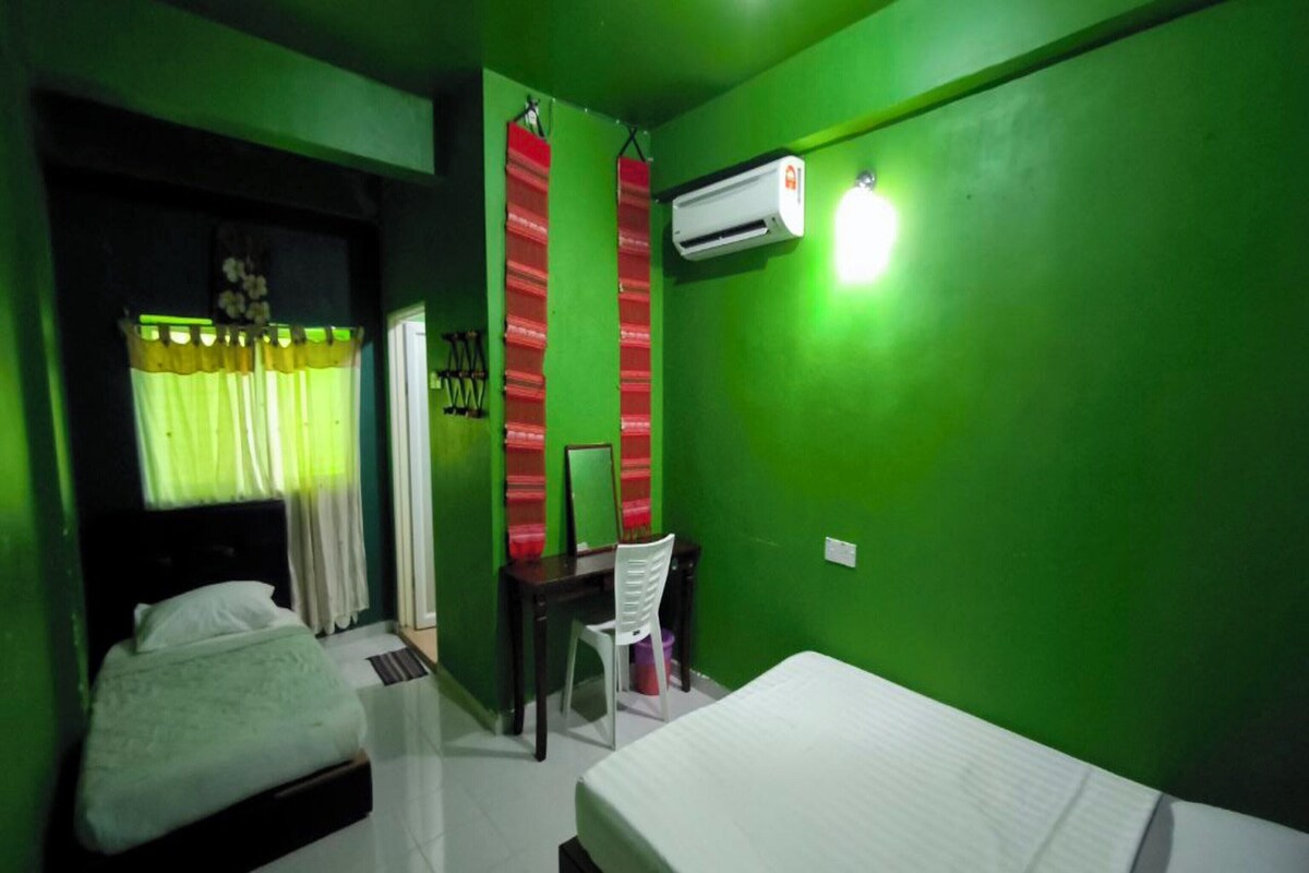 Een kamer met twee bedden, een bureau en een airconditioner.