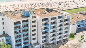 Un hôtel à plusieurs étages doté de balcons, d’une terrasse sur le toit et offrant une vue sur la plage.