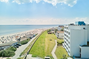 Un hôtel situé sur la côte, avec un bâtiment long et étroit attenant à une plage, comprenant un espace de stationnement et une pelouse.