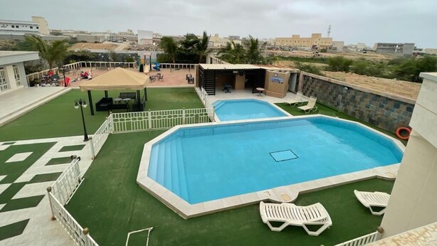 Un espace piscine sur le toit, comprenant deux piscines, un espace salon couvert et une vue sur le paysage urbain environnant.
