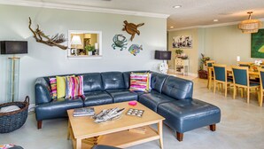 Ein Wohnzimmer mit einer Eckcouch, einem Couchtisch und einem Essbereich mit Tisch und Stühlen.
