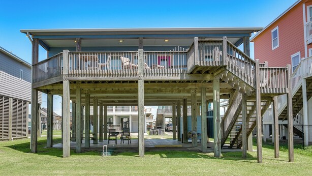 A two-story wooden deck with outdoor seating and a staircase. - Steps to Crystal Beach! Family & Pet-Friendly Home (Crystal Beach)