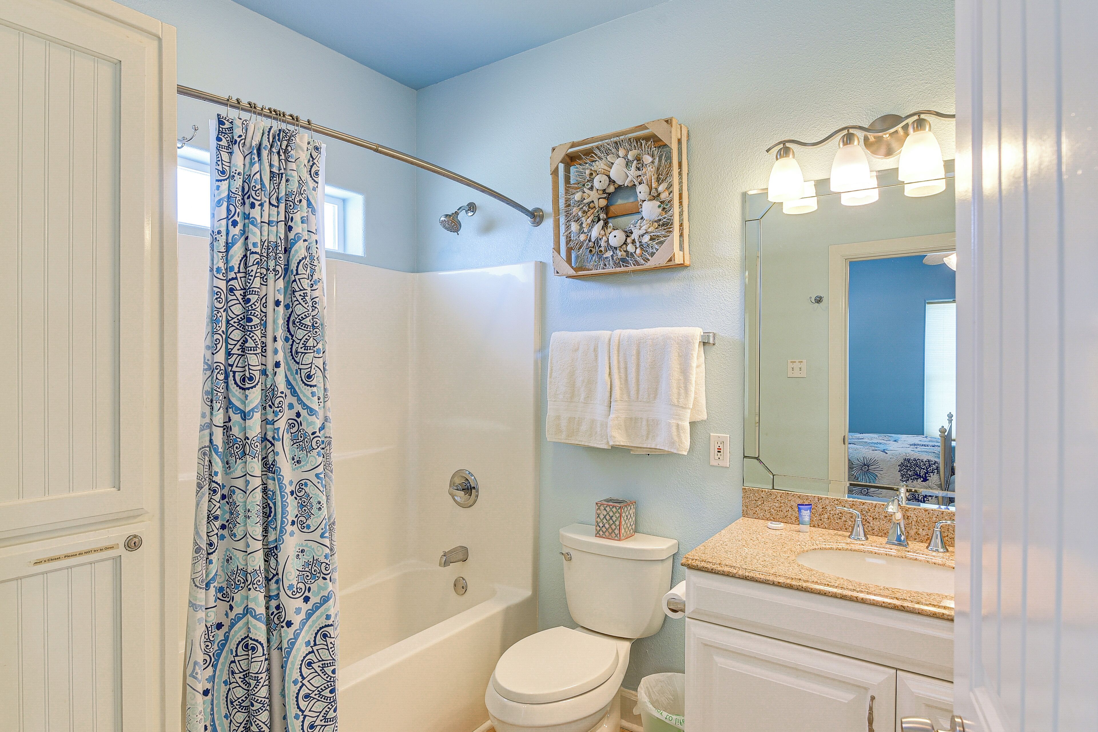 A bathroom with a shower, toilet, sink, and a mirror with lights.