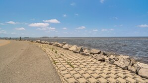 A paved waterfront road with a stone barrier and a clear blue sky. - Gulf of Mexico Beach Cottage: Walk to Boat Ramp! (Horseshoe Beach)