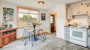 Una cucina con mobili in legno, un piano cottura bianco e un'area con sgabelli da bar.