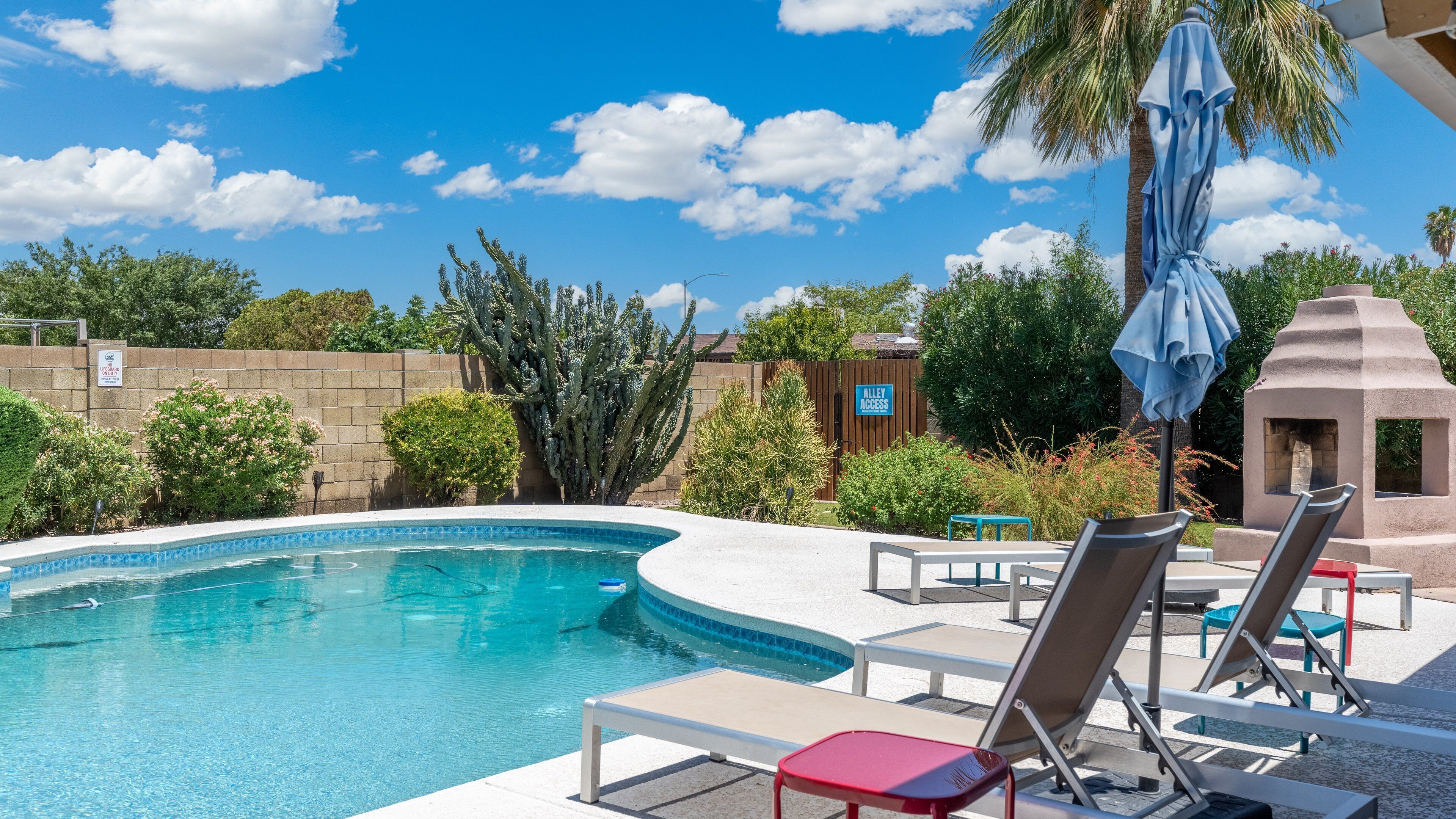 A swimming pool with lounge chairs and a barbecue area.