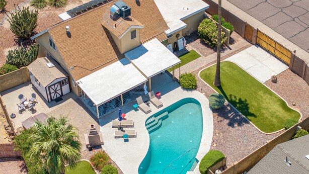 Ein Wohnhaus mit Swimmingpool, Terrassenmöbeln und einer überdachten Sitzgelegenheit im Freien.